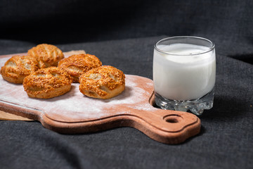 Food on a wooden board.
Baking, rolls, bread, bakery food. Milk in a glass.