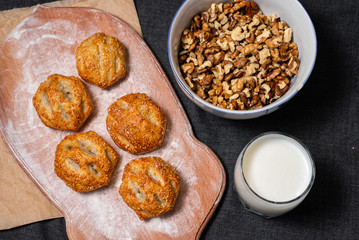 Food on a wooden board.
Baking, rolls, bread. Milk in a glass.
Sprinkled nuts