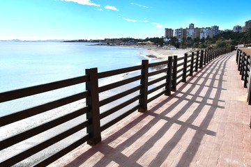 Obraz premium Mediterranean Sea coastal resting area in Campoamor, Alicante. Pedestrian path along the sea. Empty beaches during coronavirus quarantine