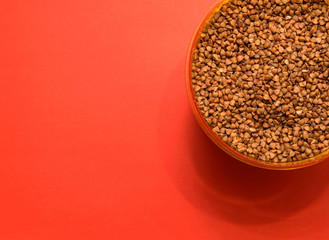 uncooked buckwheat in a plastic container on a red