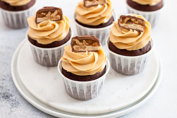 Homemade chocolate dough cupcakes with peanut butter frosting and snickers bites. Selective focus