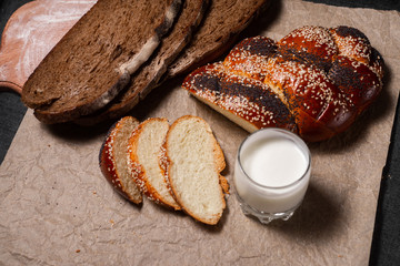 Baking, dark bread, cookies and rolls on a dark background.
Kraft paper. Milk in a transparent glass.