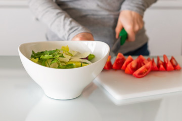 woman chopping tomatoes on kitchen. Salad preparation. Healthy lifestyle and nutrition concept.