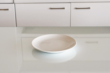 Empty glass white plate in her hands in the kitchen. No food, diet, Rising food, concept
