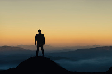 Silhouette of businessman on mountain with sunset sky background. Business success and leadership concept. - obrazy, fototapety, plakaty