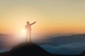 Silhouette of businessman on mountain with sunset sky background. Business success and leadership...