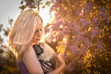 Beste Freunde - ein Kind hat im Garten sein Meerschweinchen auf dem Arm und beide genießen in der Natur den Sonnenuntergang 