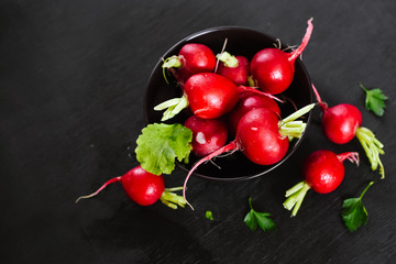 Fresh raw red radish in plate on the black wooden background
