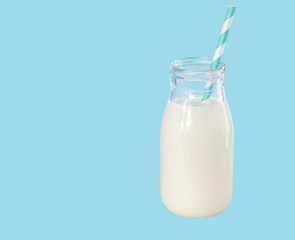 Bottle of fresh milk with straw on light blue background, food healthy concept