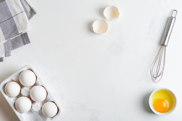Ceramic box with natural organic farm eggs and metal whisk on a stone kitchen table.