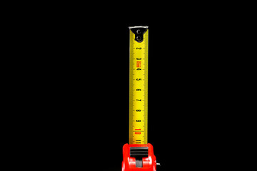 repair and construction concept. red with black construction roulette isolated on a black background close up. front view with copy space for text