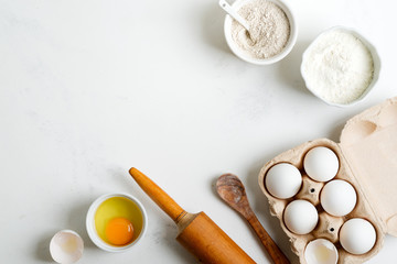Baking ingredients for making homemade traditional bread or cakes on a light grey marble background.