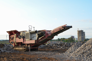 Fototapeta na wymiar Mobile Stone Jaw crusher machine for crushing concrete into gravel and subsequent cement production. Salvaging and recycling of the demolition construction waste on landfill. Reuse concrete.
