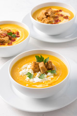 Butternut squash cream soup with milk cream, bacon, croutons, feta cheese and parsley