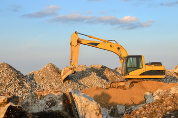 Excavator at construction site or mining quarry for crushing old concrete into gravel and subsequent cement production. Backhoe at landfill with concrete demolition waste. Salvaging and recycling