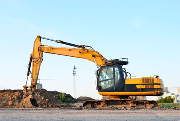 Excavator with a large iron bucket on a construction site during road works. Backhoe dig the ground for the foundation, laying storm sewer pipes. Installation of water main systems.