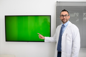 man male doctor professor teacher in medical office wearing a white lab coat and tie shirt showing to students green wall srceen research covid19 and coronavirus seminar