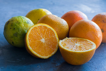 A group of oranges and lemons and one orange cut. Healthy fruit.