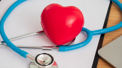 Red heart on stethoscope and white clipboard. Doctor's day, health and medication concept.