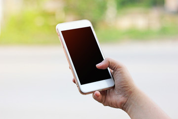 Cropped shot view of woman's hands holding smart phone with blank copy space screen for your text message or information content. Female’s hand holding smart phone with green blur background.