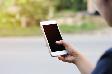 Cropped shot view of woman's hands holding smart phone with blank copy space screen for your text message or information content. Female’s hand holding smart phone with green blur background.
