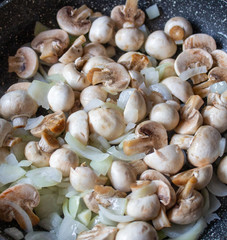 Mushrooms with onions in a frying pan. Preparing lunch and dinner.