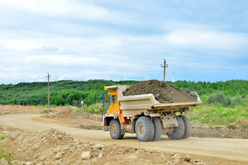 Obraz premium Big mining truck transport of minerals in the quarry. Open-cast mining of extracting rock or minerals from the earth. Largest dolomite deposit open-pit mining Gralevo, Belarus, Vitebsk region
