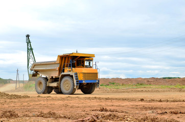 Fototapeta premium Big yellow mining truck working in the limestone open-pit. Loading and transportation of minerals in the dolomite mining quarry. Belarus, Vitebsk, in the largest dolomite deposit, quarry 