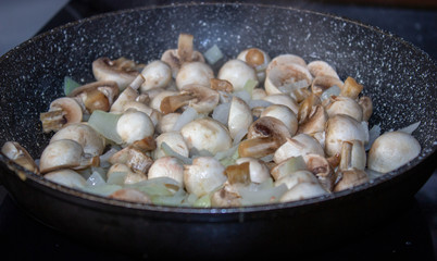 Mushrooms with onions in a frying pan. Preparing lunch and dinner.