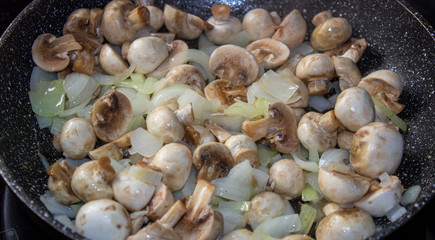 Mushrooms with onions in a frying pan. Preparing lunch and dinner.