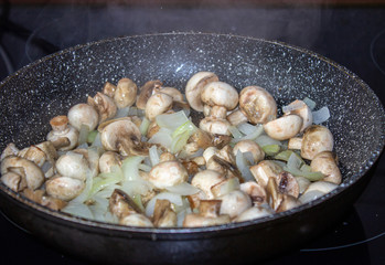 Mushrooms with onions in a frying pan. Preparing lunch and dinner.