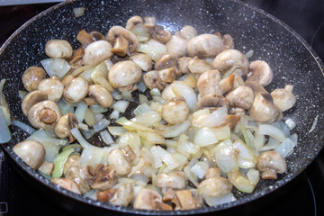 Mushrooms with onions in a frying pan. Preparing lunch and dinner.