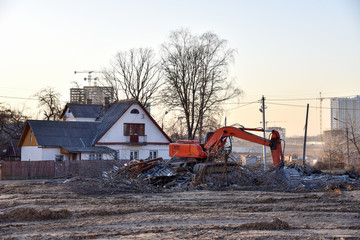 Excavator demolishes an old wooden house in the village for new construction project. Tearing Down a Houses. Building removal made of bricks. Hard equipment for demolition works