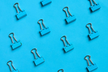 Blue binder clips pattern on blue background