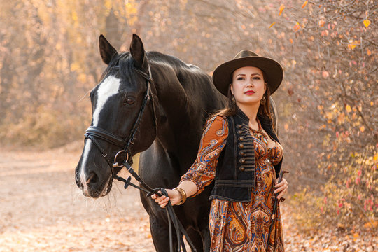 beautiful girl, a woman walks with a horse autumn road
