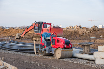 Obraz premium Road roller and excavator working at construction site during asphalt road repair. Paving roller machine on paving works.