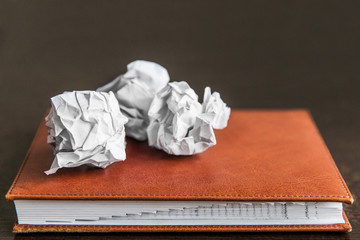 Pieces of crumpled paper on the notebook on workplace