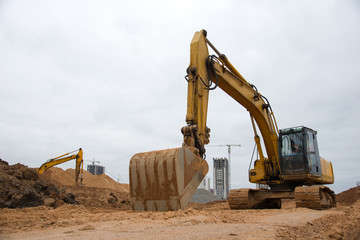 Fototapeta na wymiar Track-type excavator during earthmoving at construction site. Backhoe digging the ground for the foundation and for laying sewer pipes district heating. Earth-moving heavy equipment