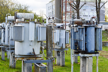 Large industrial iron metal transformer substation with transformers and high-voltage electrical equipment and wires with surge arresters to supply the city with electricity