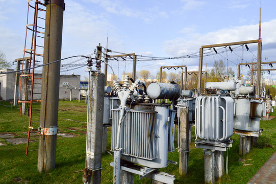 Large industrial iron metal transformer substation with transformers and high-voltage electrical equipment and wires with surge arresters to supply the city with electricity