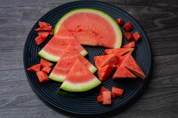 Slices of ripe watermelon in a plate on a dark background