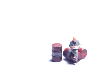 Photo Close Up, Scale HO Business Man Toy, Reading Business Report Beyond Red Barrel and dirty screw, at White Background, for your element design oil or fuel related