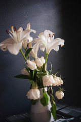 Naklejka na ściany i meble White lilies and roses against dark background