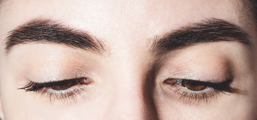 Beautiful female eyes. Brown eyes close up. Covered eyes. Eyes look down. Mascara on the eyelashes. Eyes and eyebrows near. Charming look.