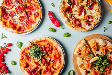 Delicious italian pizzas served on bright table  with ingredients shot from above, pizza shop