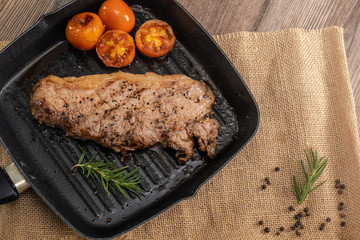 Juicy grilled steak medium rare beef on the grill pan with tomato and rosemary , wooden table - Stock photo