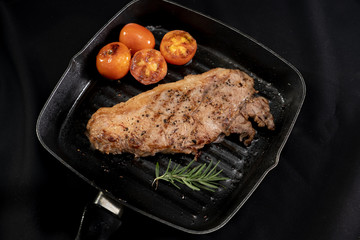 Juicy grilled steak medium rare beef on the grill pan with tomato and rosemary , black background  - Stock photo
