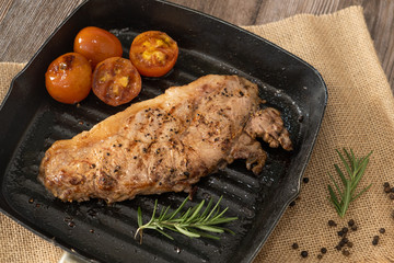 Juicy grilled steak medium rare beef on the grill pan with tomato and rosemary , wooden table - Stock photo
