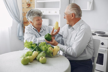 Couple in a kitchen. Grandparents sitting at home. Woman with vegetables