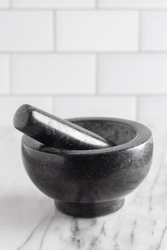 Black Stone Mortar And Pestle On A Marble Countertop